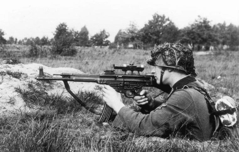 Black and white photo of a man aiming a MP44